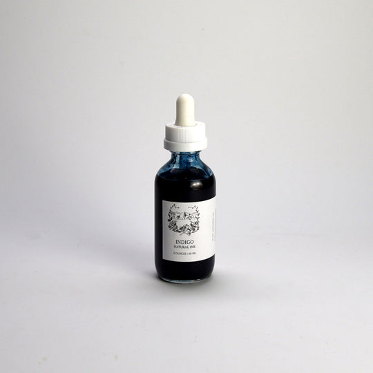 Bottle of indigo liquid with a dropper on a light gray background