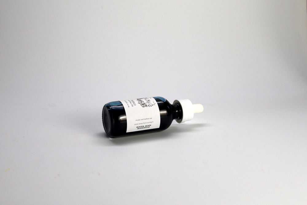 Indigo ink dropper bottle with a white label on a gray background