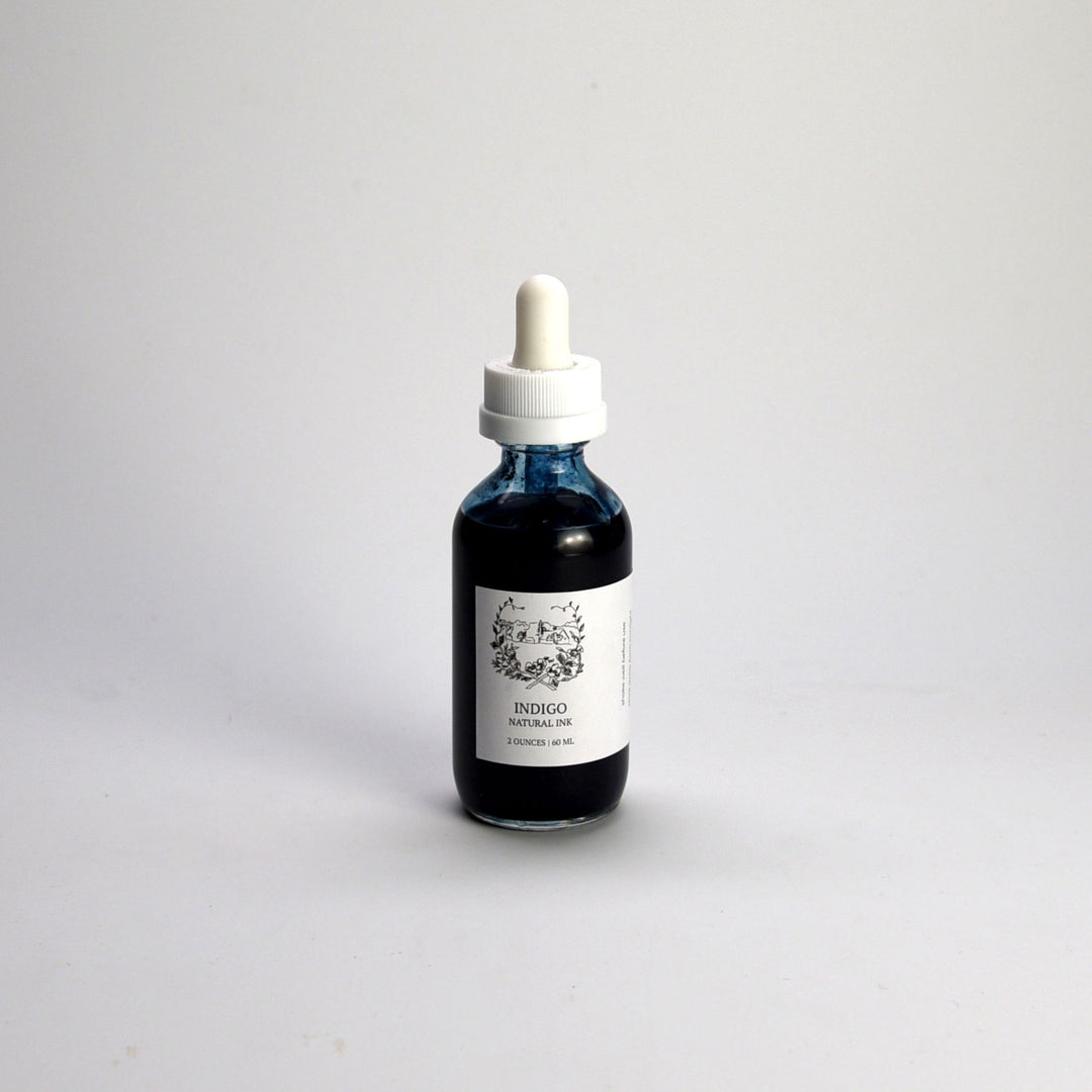 Bottle of indigo liquid with a dropper on a light gray background