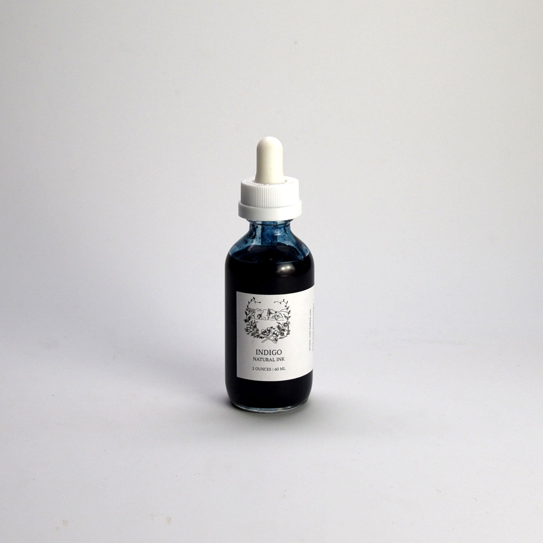 Bottle of indigo liquid with a dropper on a light gray background
