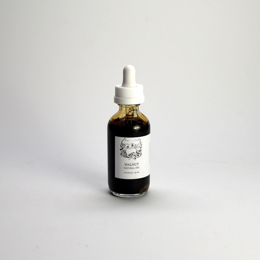 Bottle of walnut artists ink with a dropper on a white background