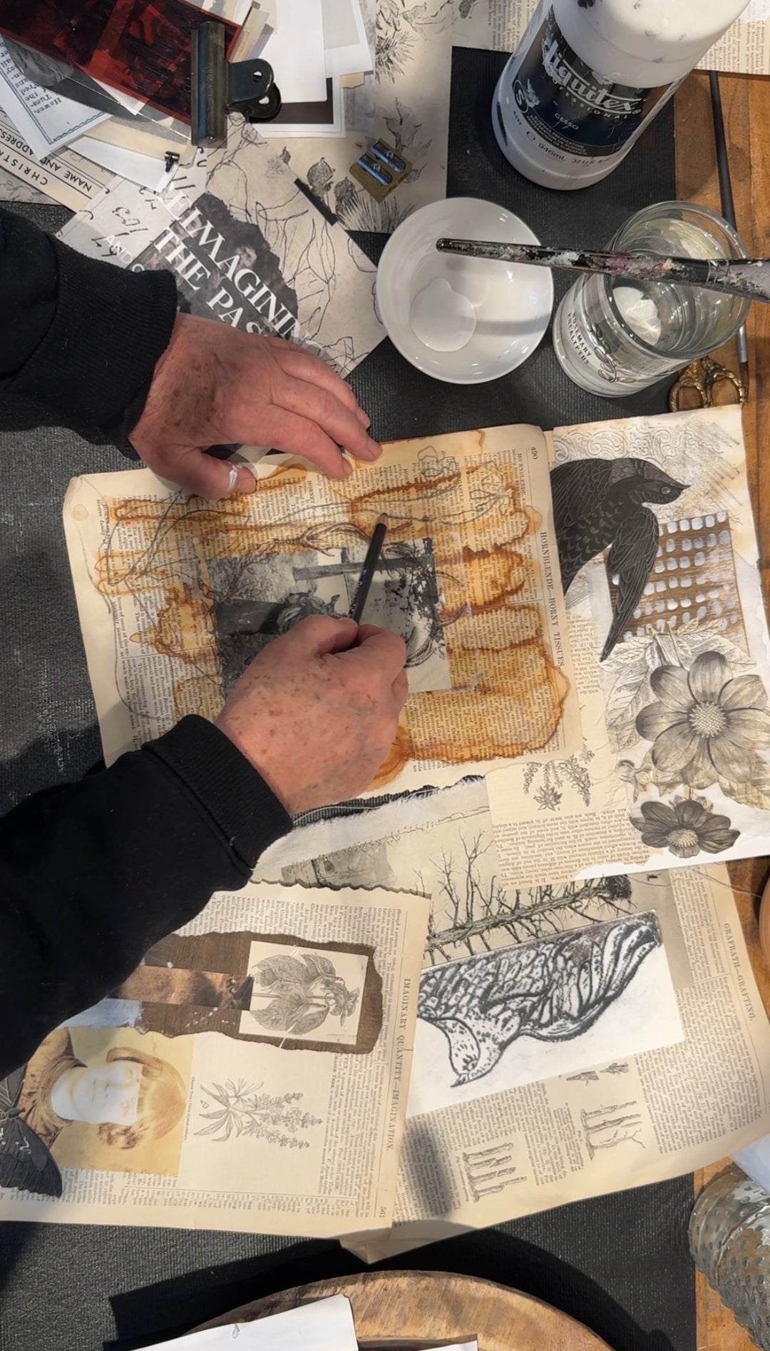 Kate Poole drawing on a textured book with various art supplies on a table.