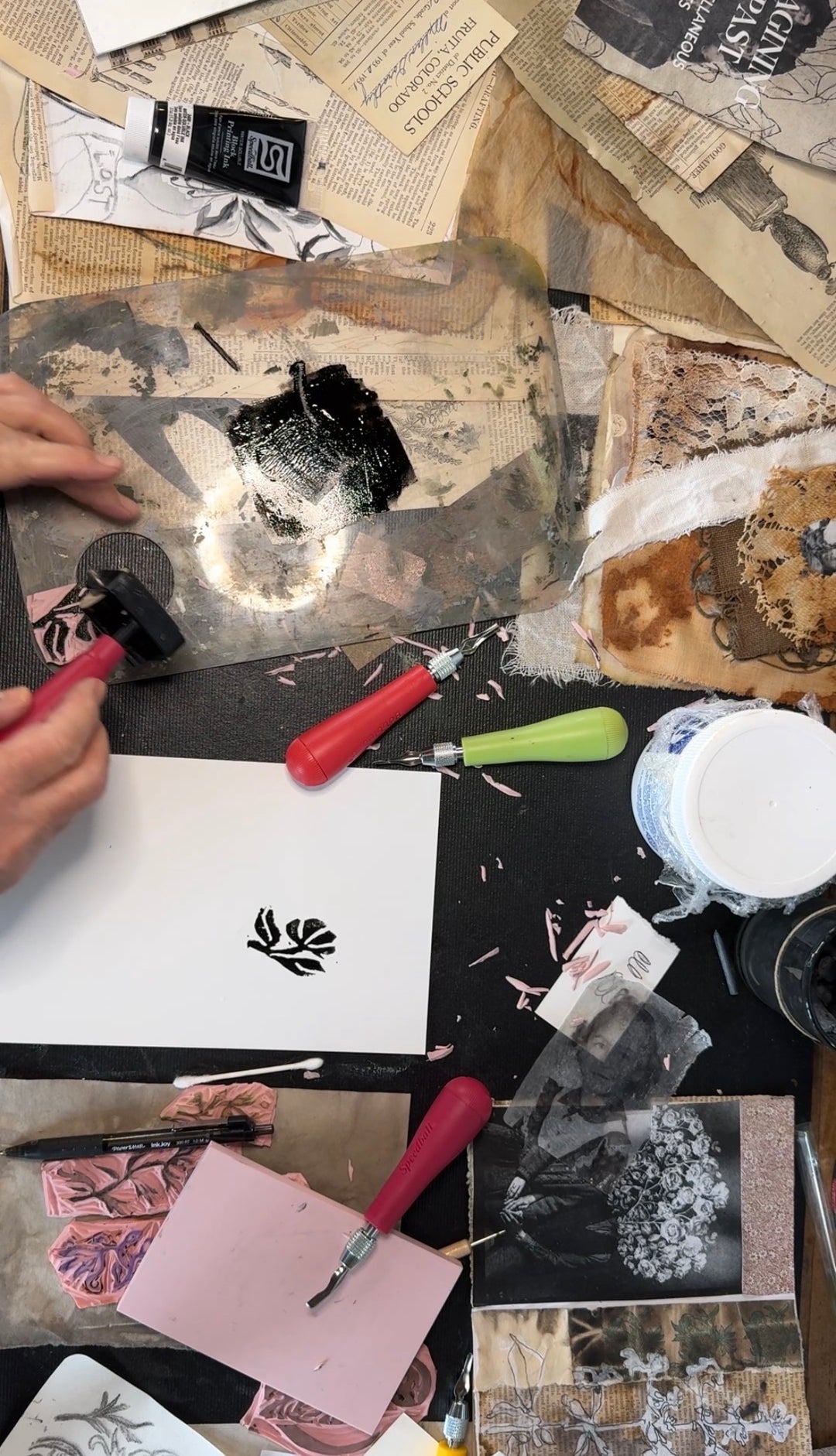 Artistic process of hand carved stamps on paper with various tools and materials.