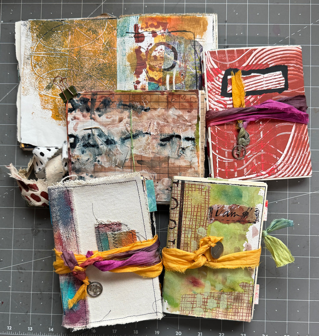 Collection of art journals with textured pages and decorative elements on a grid background