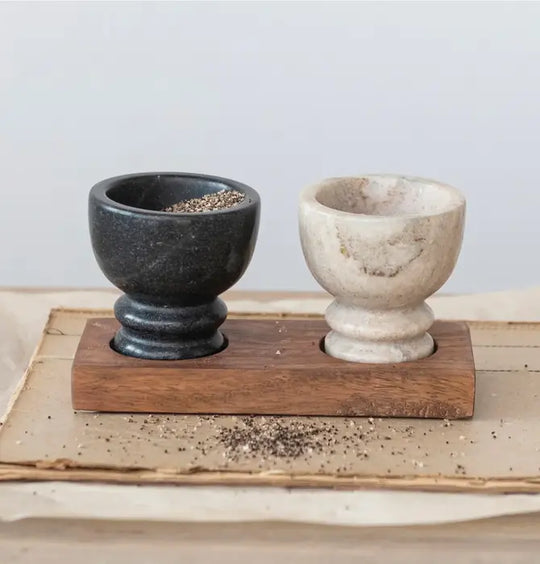 Two stone bowls on a wooden stand with a light background